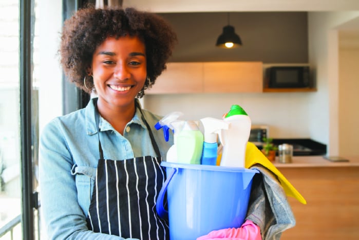 afro-woman-holding-a-bucket-with-cleaning-items_1-min