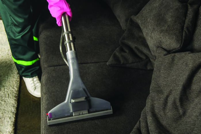 stock-photo-partial-view-person-rubber-glove-cleaning-sofa-vacuum-cleaner-min